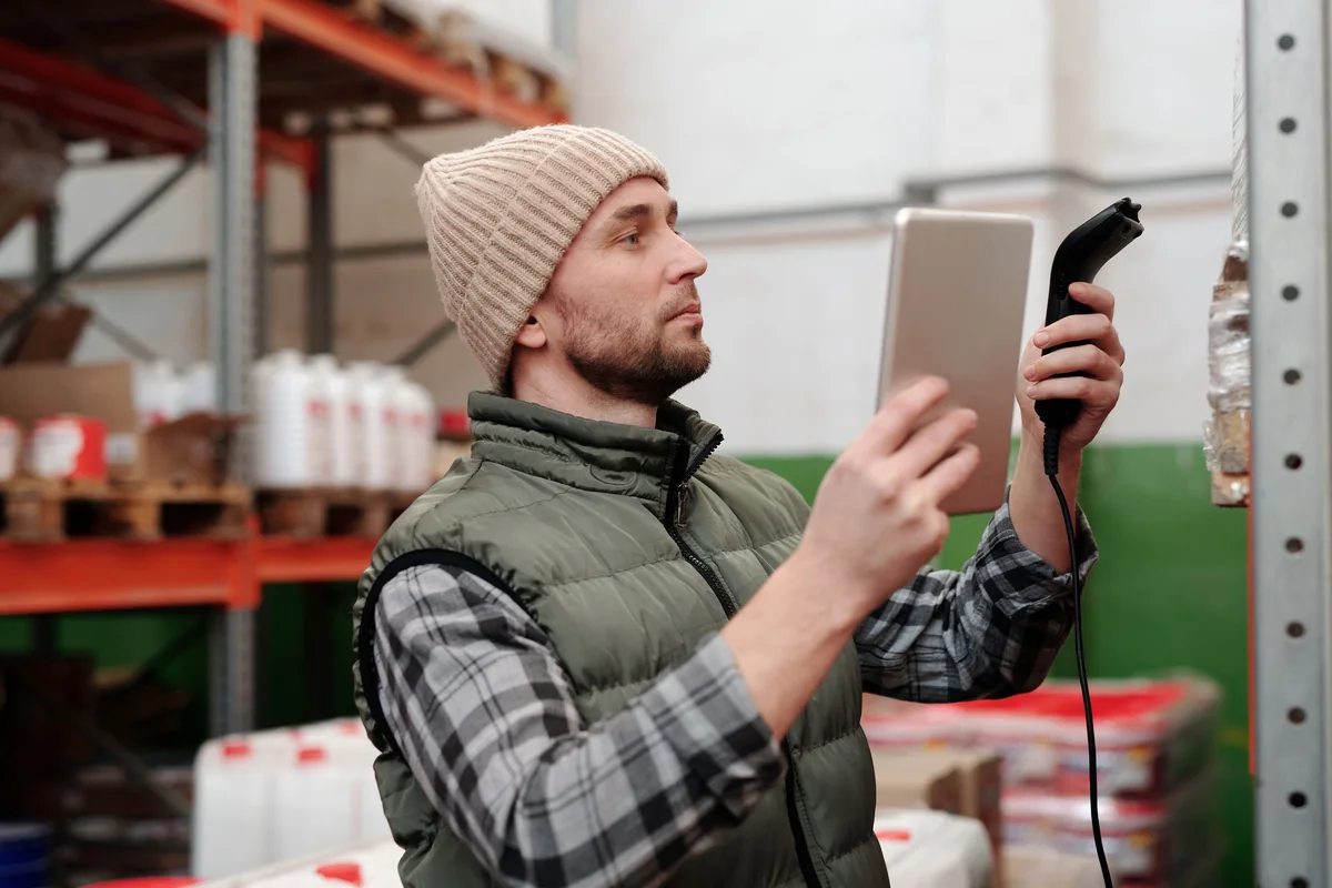 Warehouse worker checking goods with a handheld scanner and tablet